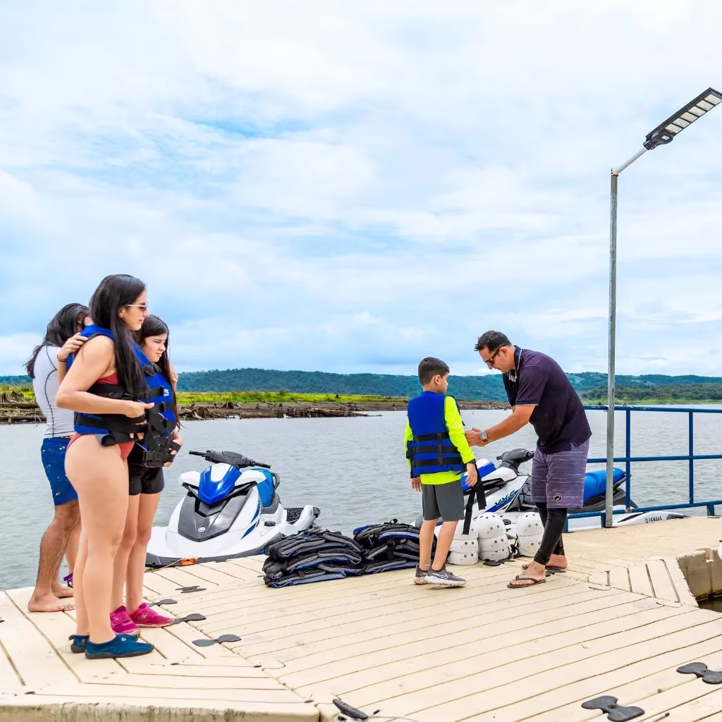 Family waiting as a guide helps a child get ready with safety gear before starting the jet ski tour on Lake Arenal, Costa Rica