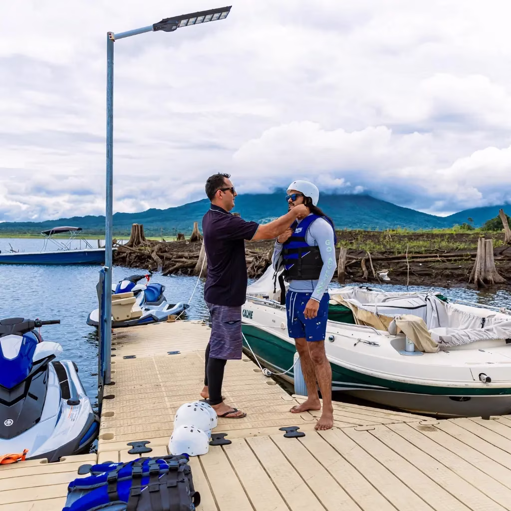Guide adjusting a helmet on a client at the starting dock before the jet ski tour on Lake Arenal, Costa Rica