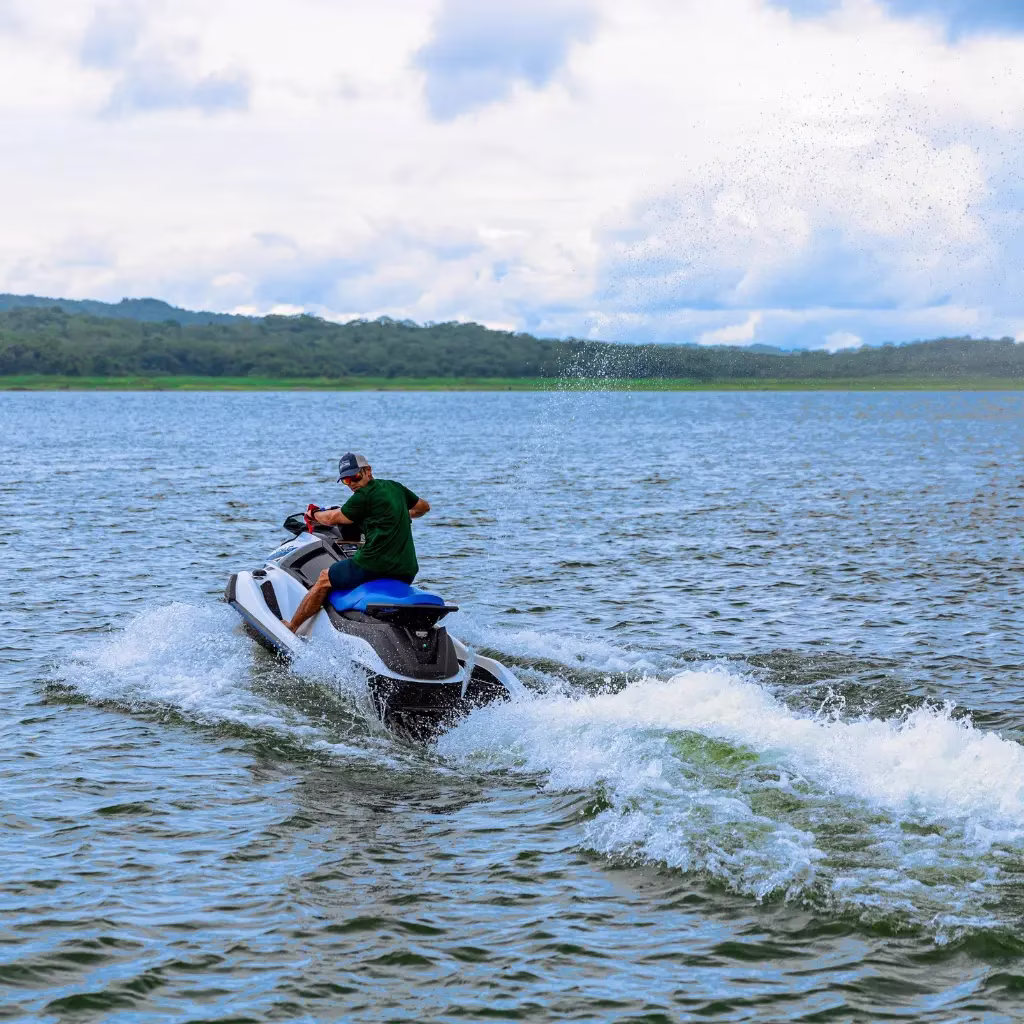 Close up of a man riding a jet ski on Lake Arenal, looking back while cruising across the water, Costa Rica