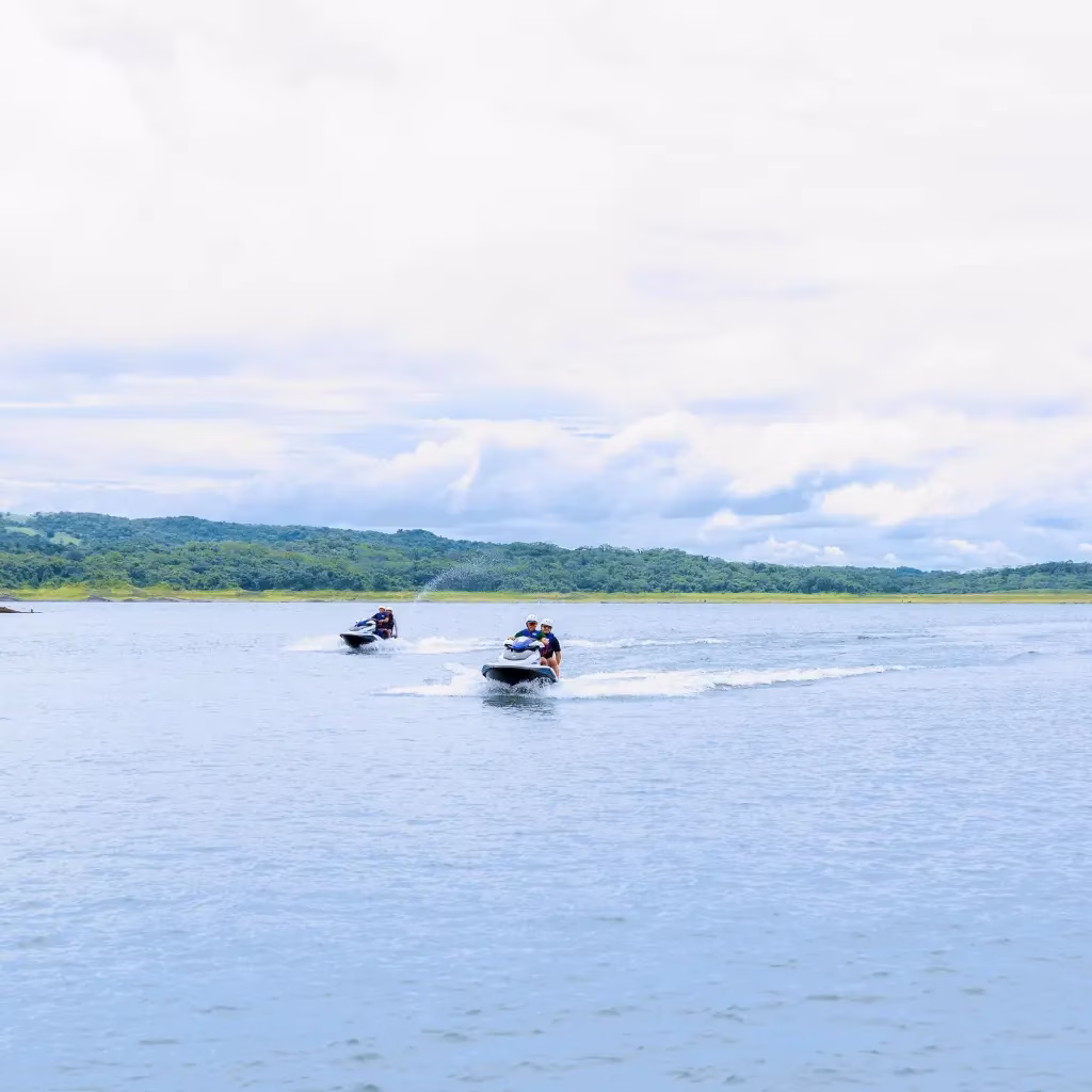 Two jet skis with riders on Lake Arenal, mountains visible in the background, Costa Rica