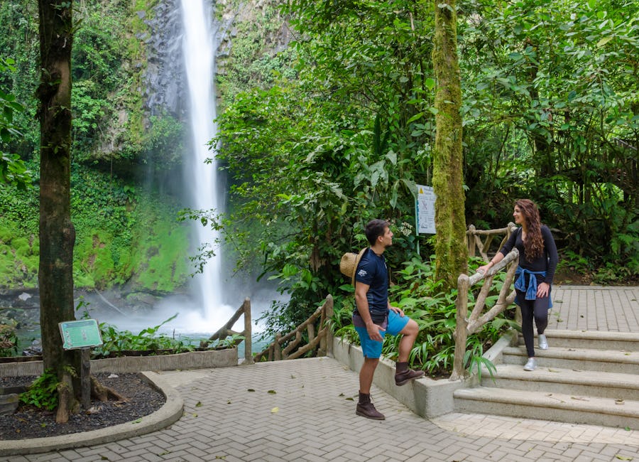 Couple resting and talking on the stairs leading down to La Fortuna Waterfall in San Carlos, Costa Rica