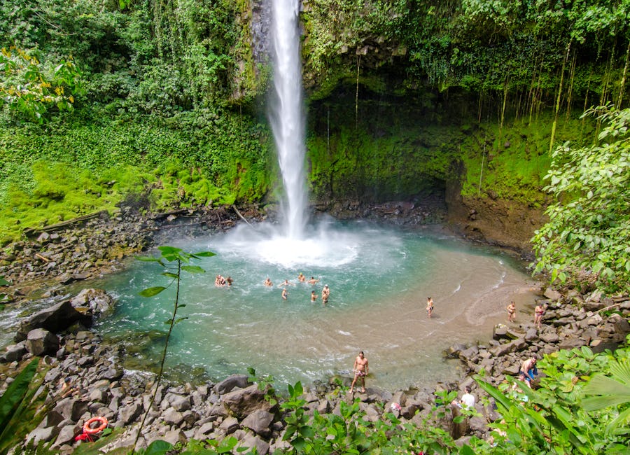Families happily swimming in the natural pool at La Fortuna Waterfall in La Fortuna, San Carlos, Costa Rica