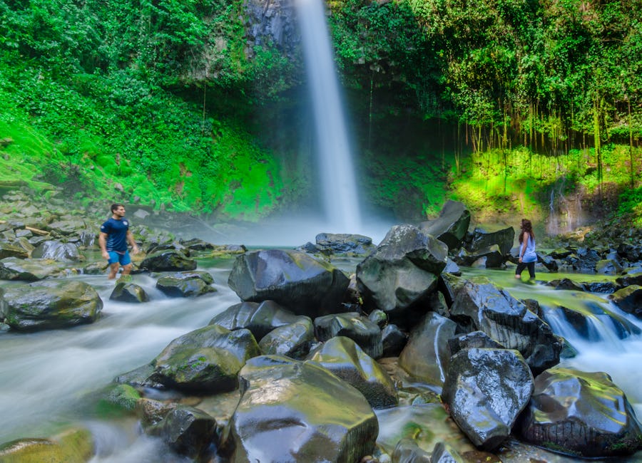 Couple standing in the river with La Fortuna Waterfall in the background in San Carlos, Costa Rica