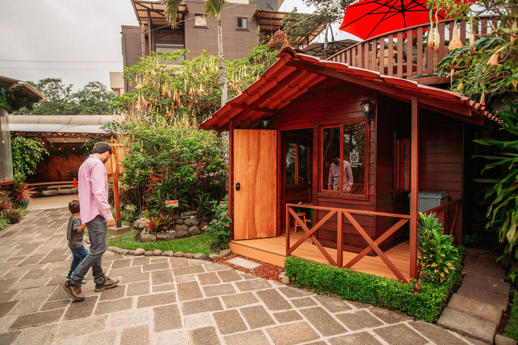 Father guiding his child toward the wooden kids house play area at Hotel & Spa Poco a Poco, Monteverde
