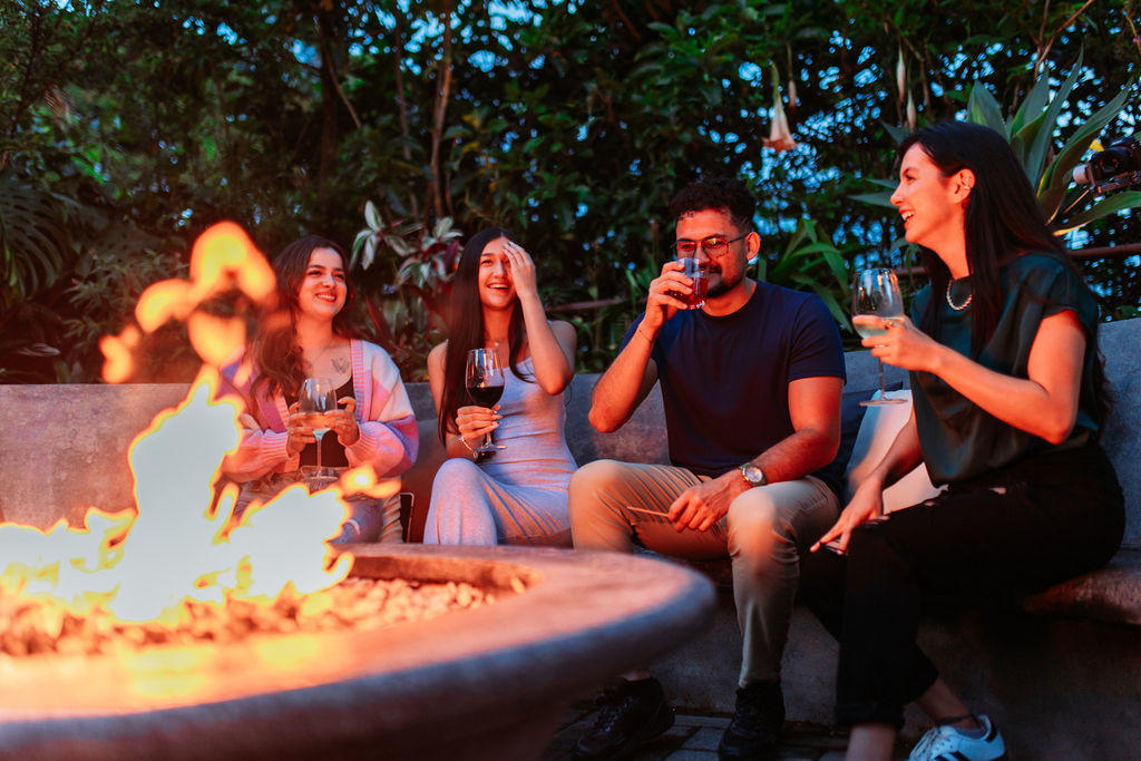 Close up of friends enjoying the fire pit with flames in the foreground at Hotel & Spa Poco a Poco, Monteverde