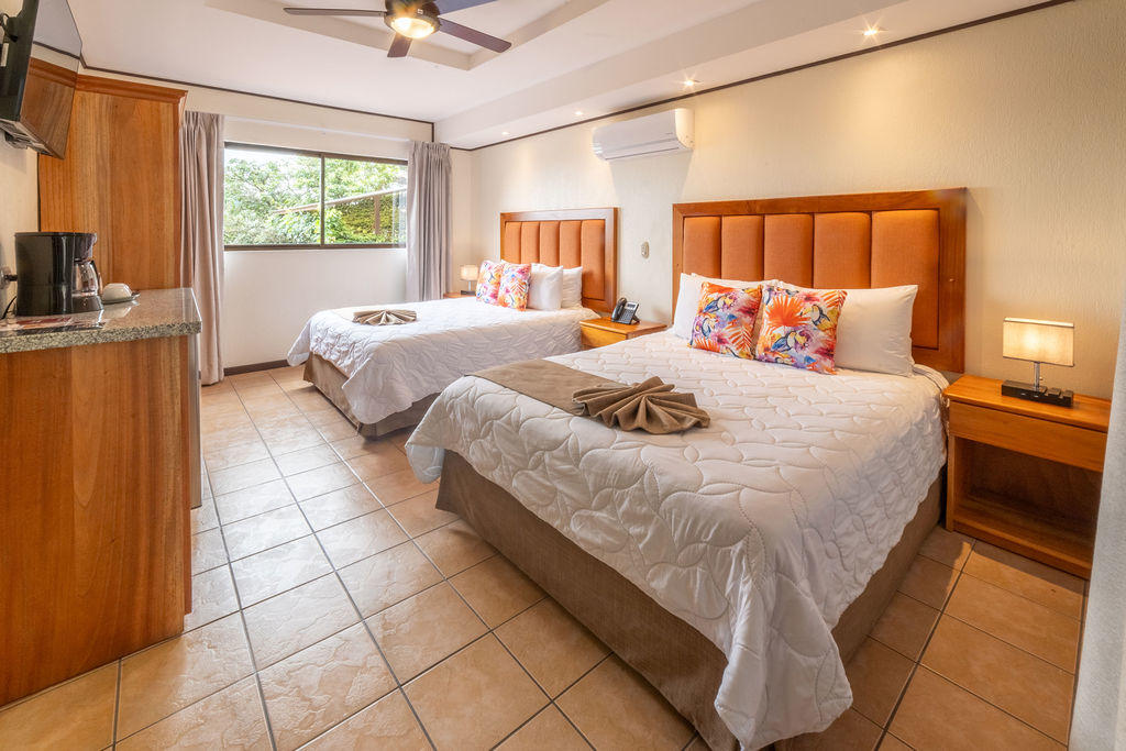 Bromelia Room corner view with two king beds, amenities, and a window in the background at Hotel & Spa Poco a Poco, Monteverde