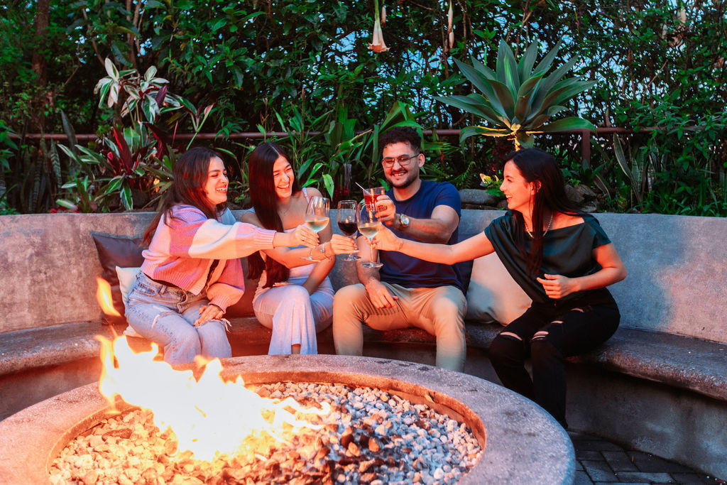 Friends toasting drinks around the fire pit at Hotel & Spa Poco a Poco, Monteverde