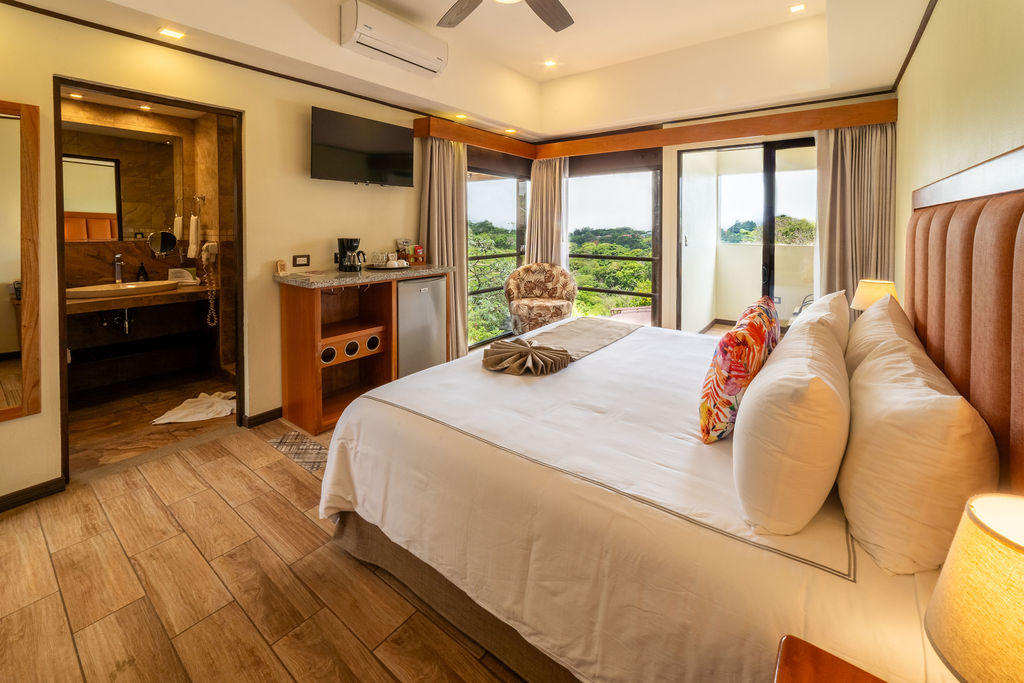 Quetzal Room with a king bed, nature views outside, and an open bathroom in the background at Hotel & Spa Poco a Poco, Monteverde