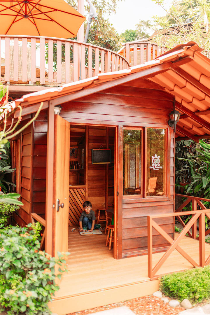 Full view of the wooden kids house with open door and child painting inside at Hotel & Spa Poco a Poco, Monteverde