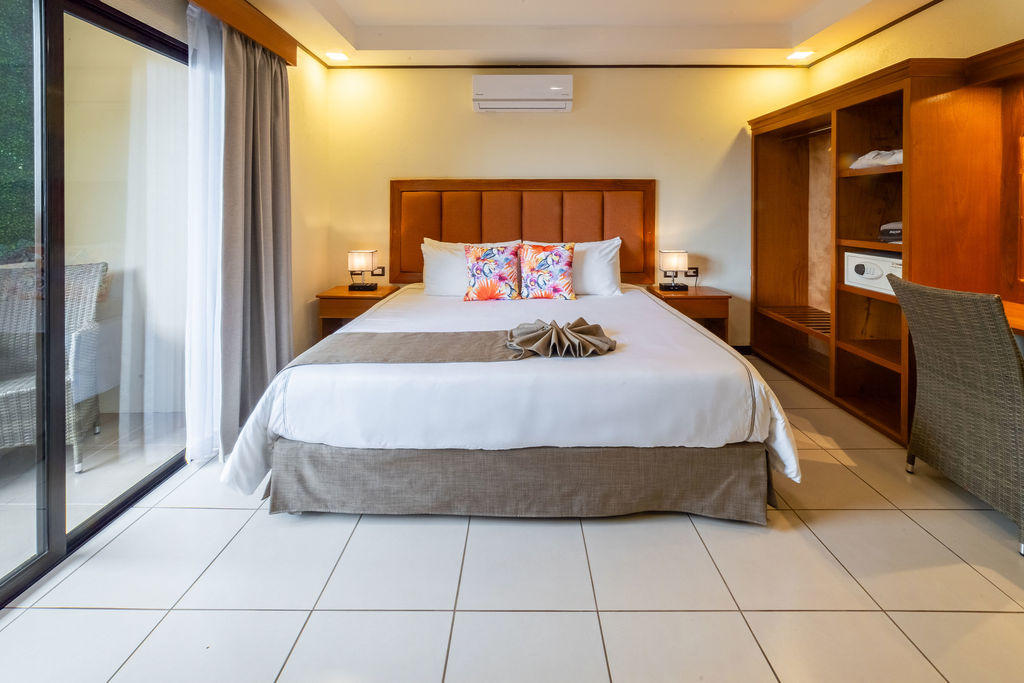 Bromelia Room front view with a king bed, amenities, and balcony doors on the left at Hotel & Spa Poco a Poco, Monteverde