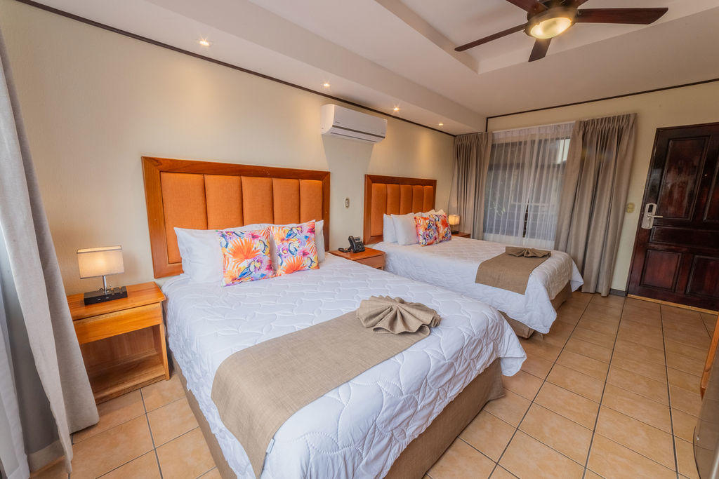 Bromelia Room from another angle with two king beds, amenities, and the entrance door in the background at Hotel & Spa Poco a Poco, Monteverde