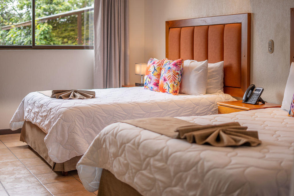 Bed detail in Bromelia Room featuring two king beds with comfortable bedding at Hotel & Spa Poco a Poco, Monteverde
