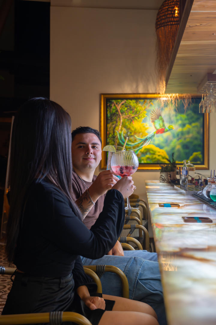Couple toasting drinks at the bar, showing a man facing forward and a woman from behind at Hotel & Spa Poco a Poco, Monteverde