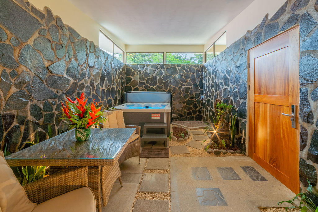 Extended view of the jacuzzi area with side table and entrance door visible in Forest Deluxe with Jacuzzi at Hotel & Spa Poco a Poco, Monteverde