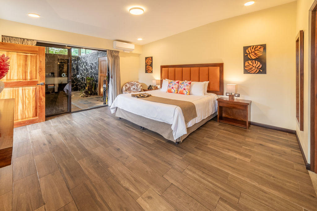 Wider view of Forest Deluxe room with king bed, nightstands, and access to private jacuzzi area at Hotel & Spa Poco a Poco, Monteverde