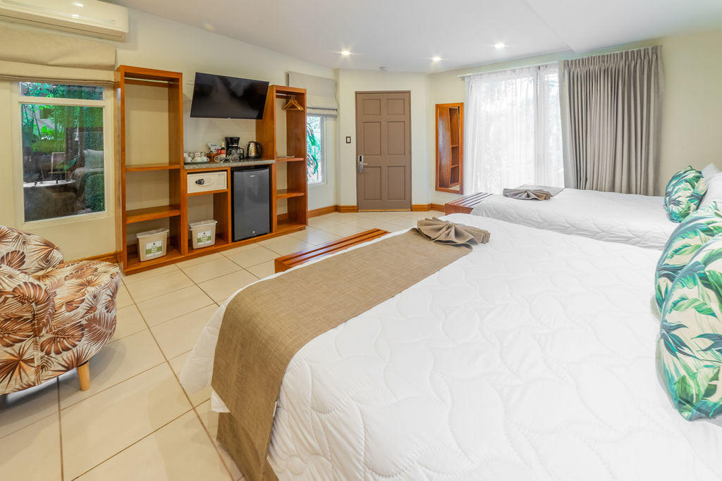 Rear wall view of Garden Family Room showing queen and king beds, TV wall, and amenities at Hotel & Spa Poco a Poco, Monteverde
