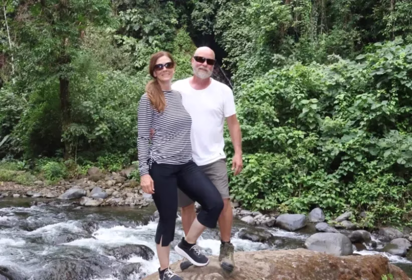 Senior couple posing on river rocks during a nature stop on an ATV tour in La Fortuna, Costa Rica
