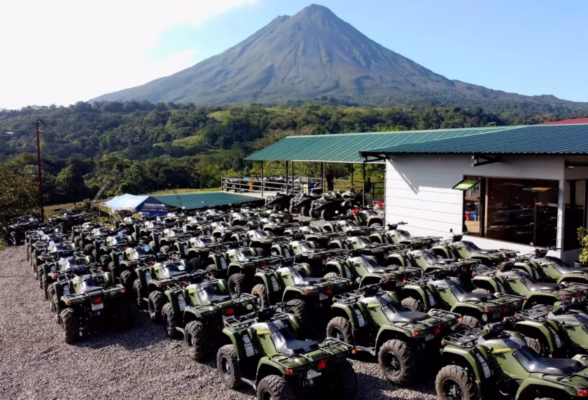 Tour base with a fleet of green ATVs and Arenal Volcano in the background in La Fortuna, Costa Rica