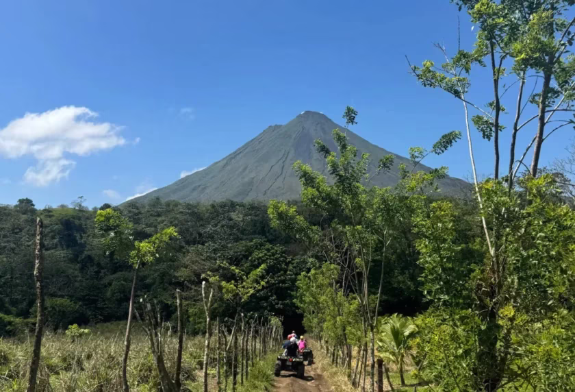 Off road trail through a private farm with two ATVs riding toward Arenal Volcano in La Fortuna, Costa Rica