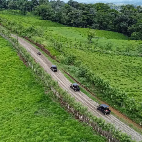 Aerial view of three side by side UTVs driving through farmland trails during a tour in La Fortuna, Costa Rica