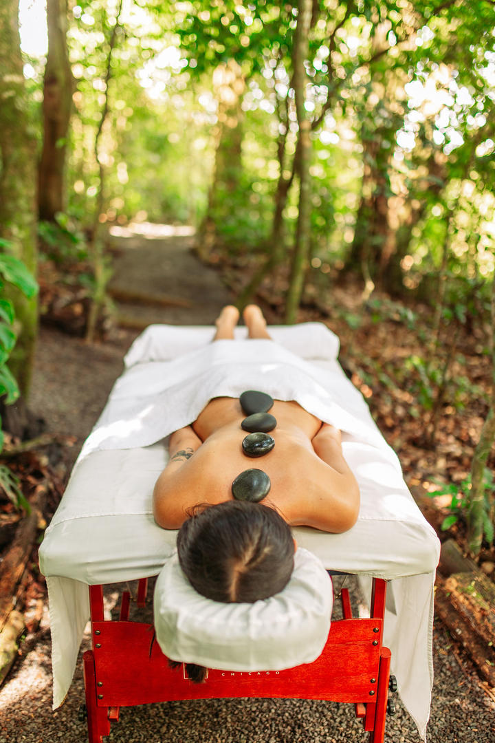 Woman receiving a hot stone massage outdoors in a forest setting at Naroa Spa, Monteverde Country Lodge, Monteverde, Costa Rica