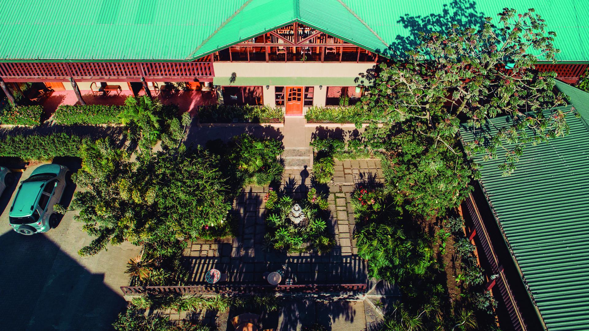 Aerial drone view of the main building with parking area and front gardens at Monteverde Country Lodge, Monteverde, Costa Rica
