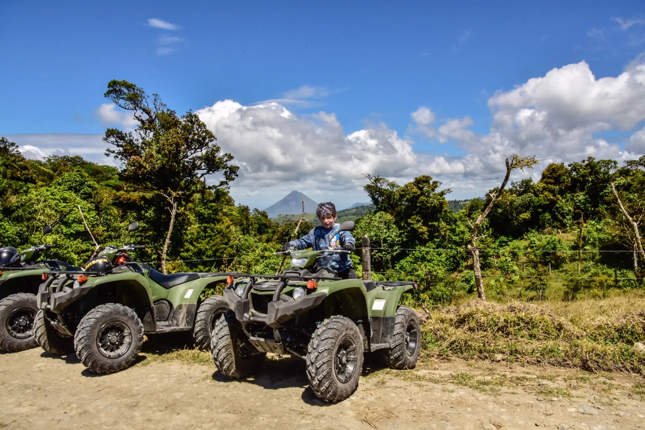 Boy posing on a parked ATV along a farm trail looking at the camera in La Fortuna, Costa Rica