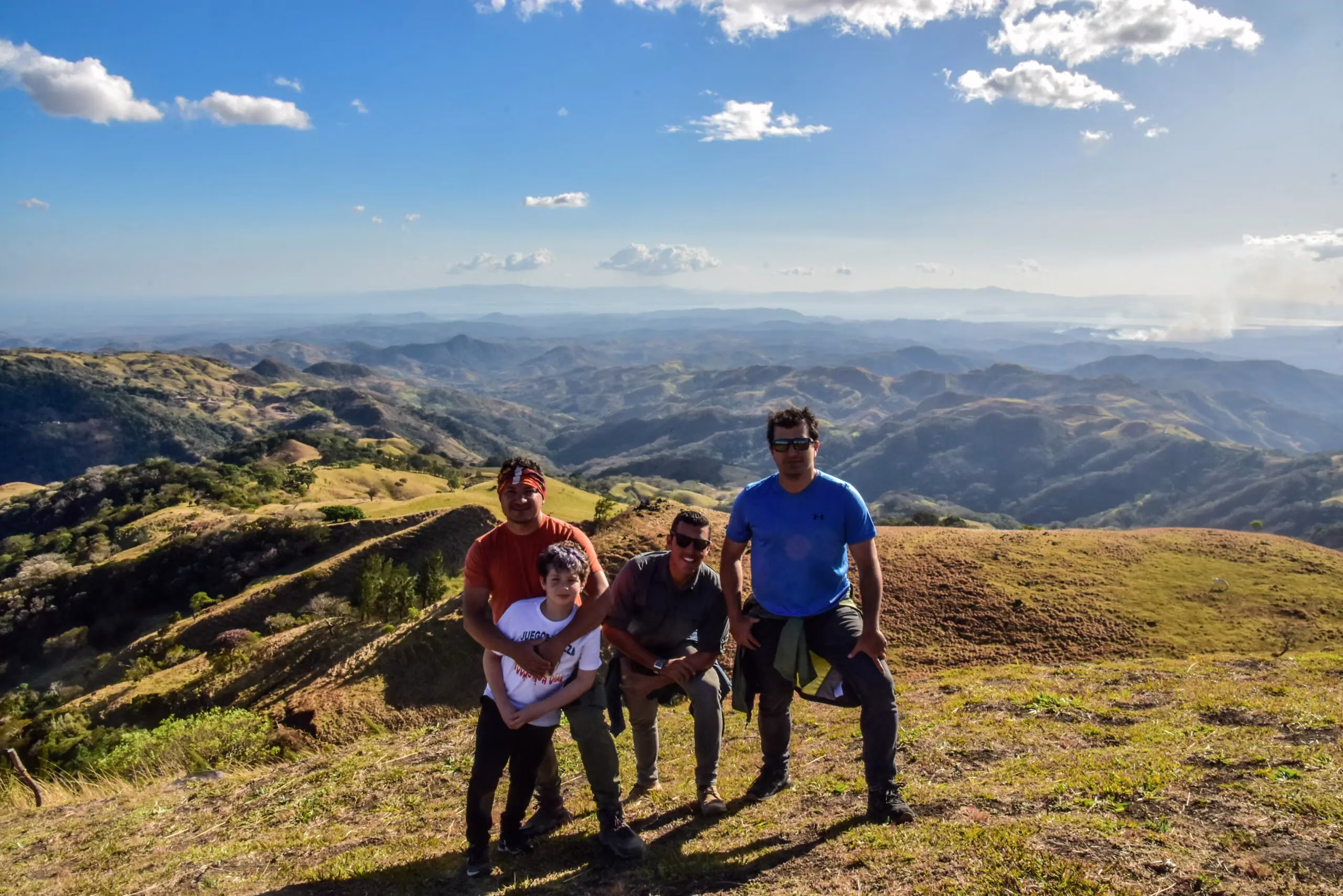 Family of four posing at a scenic viewpoint overlooking the Northern Plains during an ATV tour in La Fortuna, Costa Rica