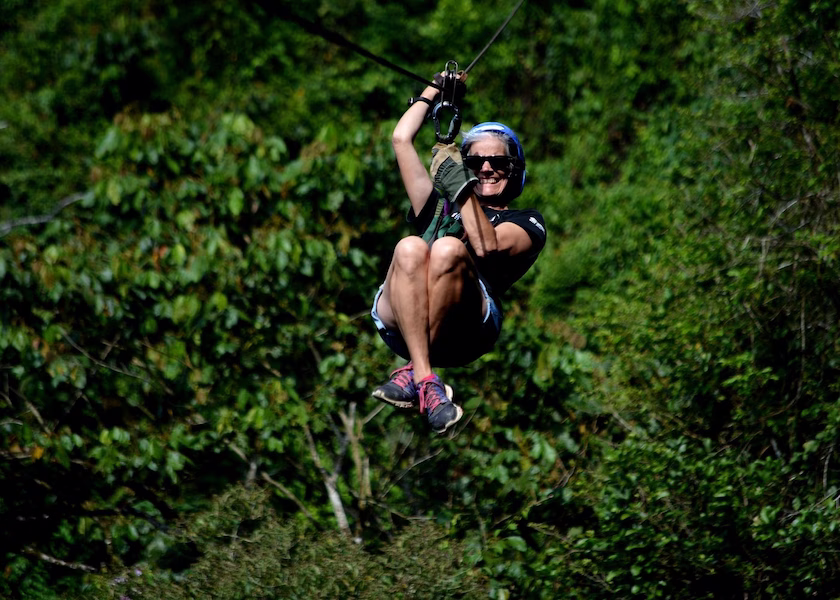 Woman enjoying ziplining with tropical forest views in Arenal