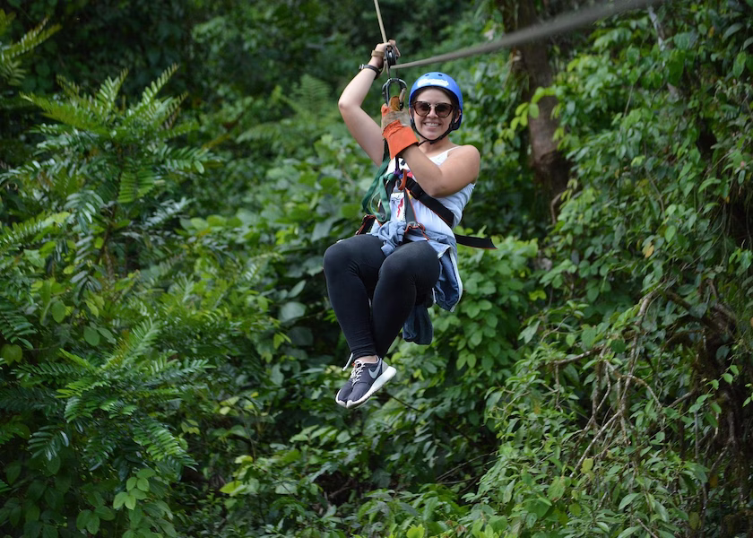 Smiling woman ziplining through the Arenal rainforest