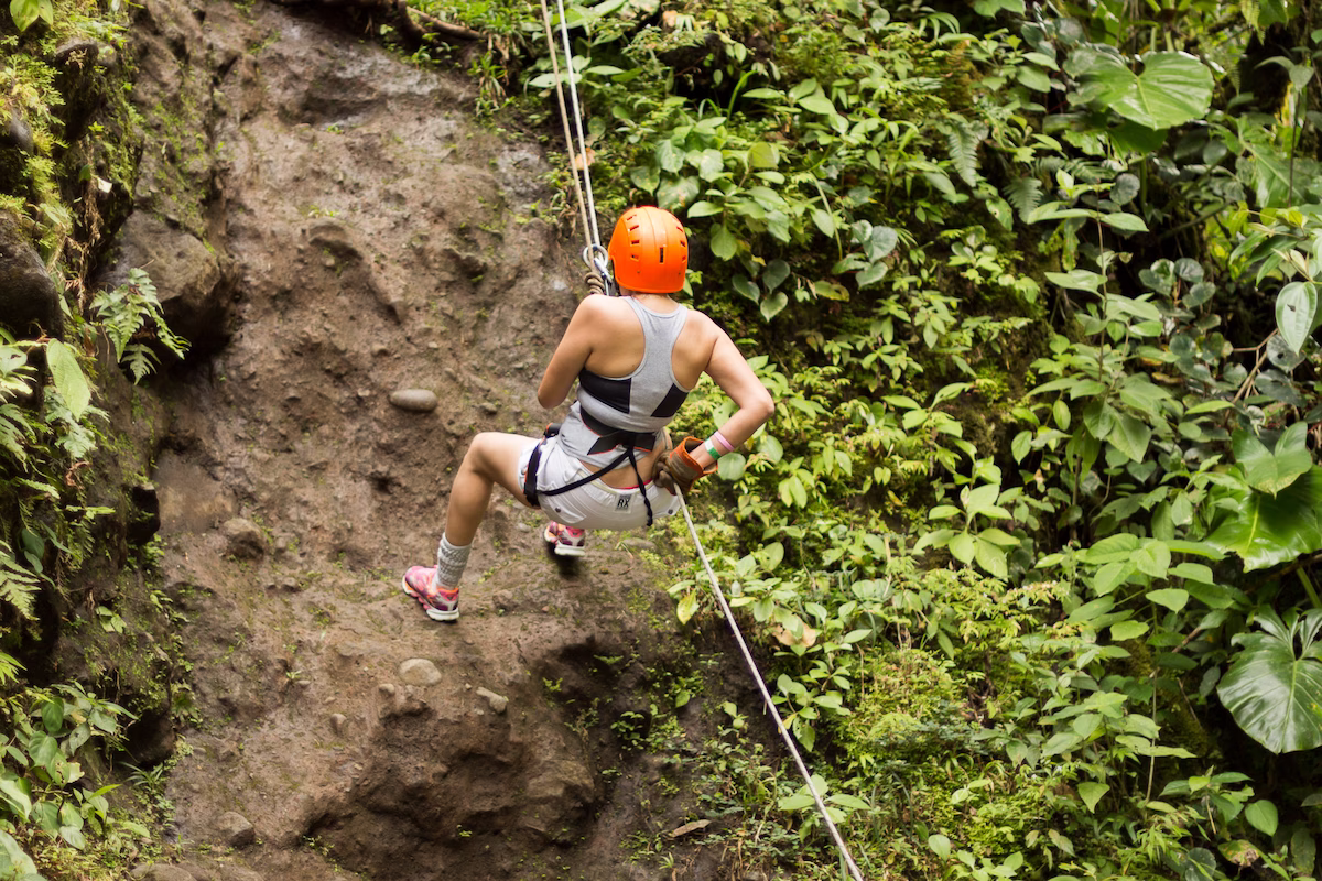 Woman rappelling in Arenal, descending a cliff over 50 meters high
