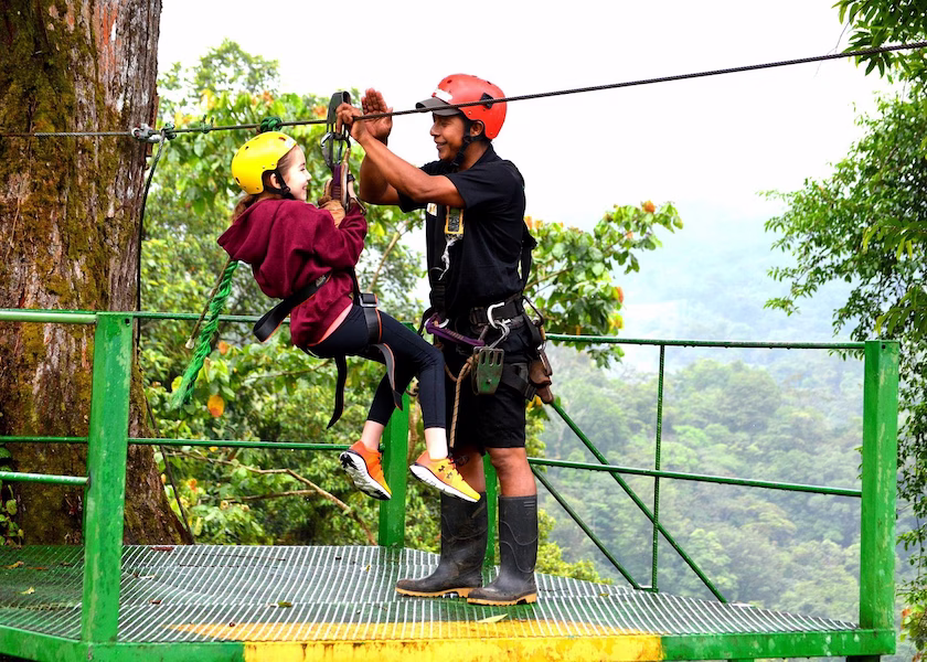 Girl assisted by a guide on the zipline launch platform