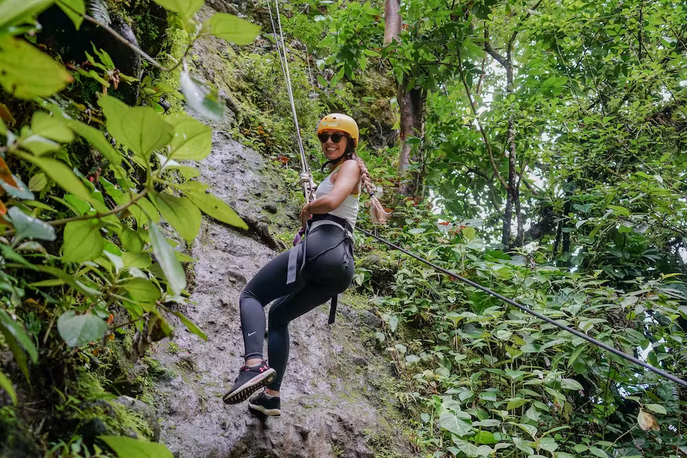 Woman smiling while rappelling down a cliff over 50 meters high
