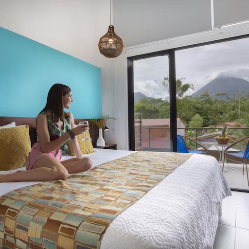 Woman relaxing on a bed holding a cup of coffee at La Fortuna Lodge, La Fortuna, Costa Rica