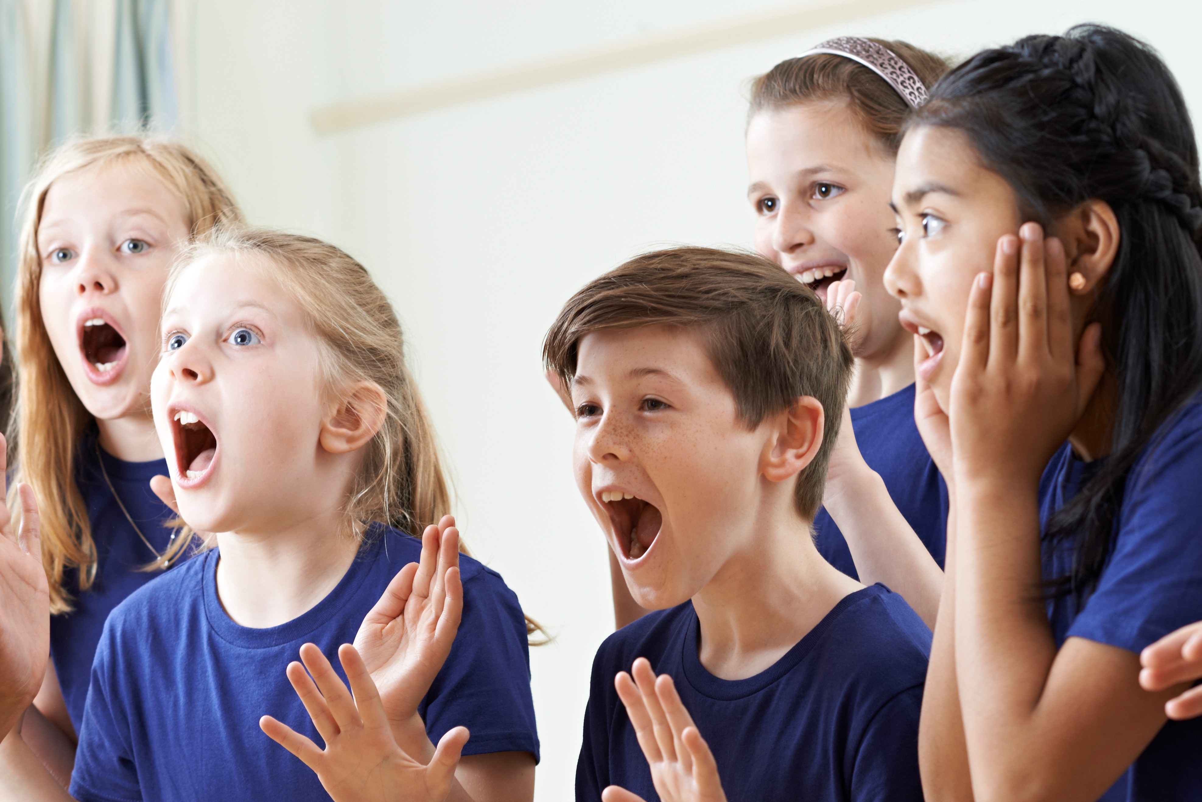 A group of 5 children in blue t-shirts looking surprised and shocked