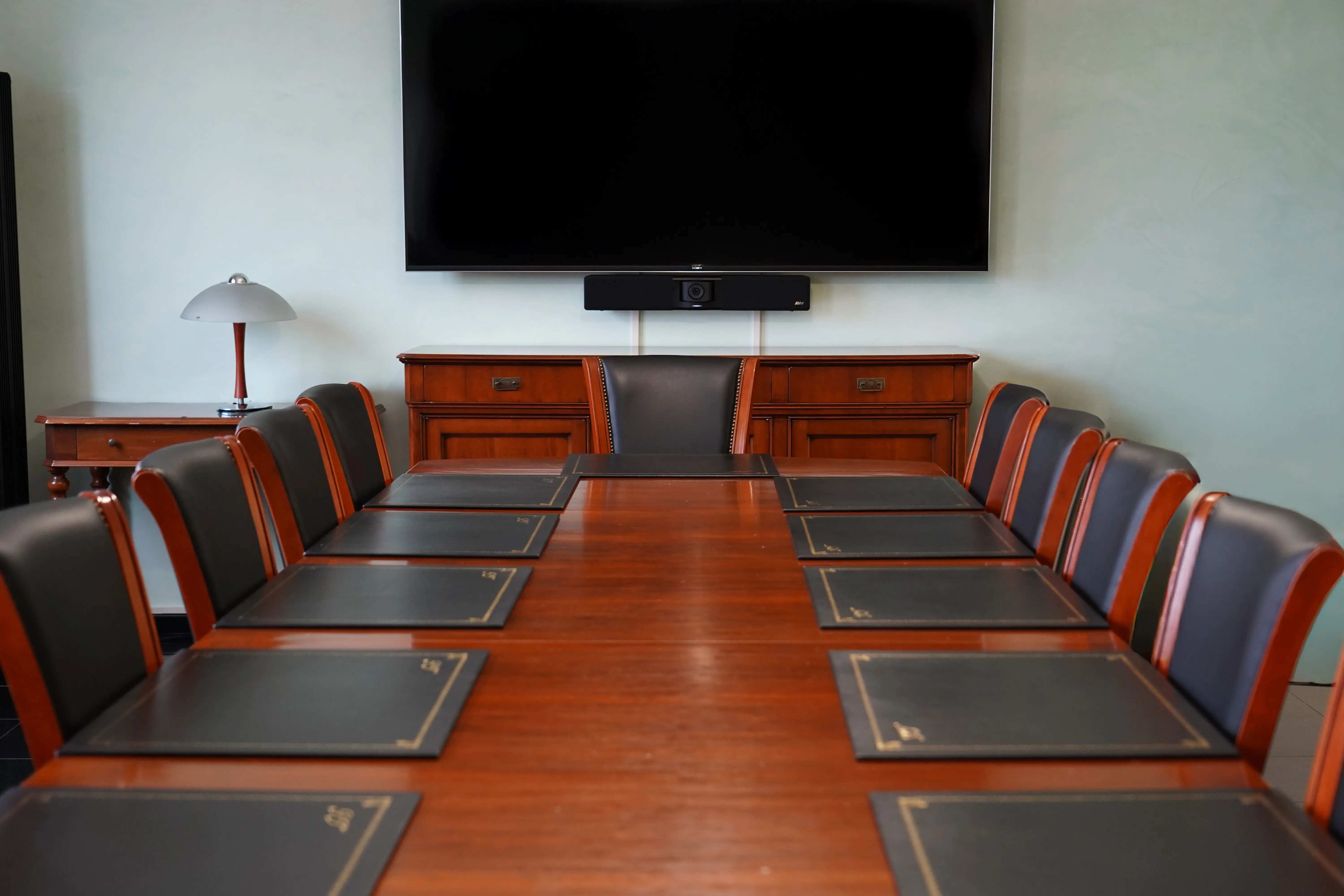 Una lunga tavola da conferenza lucida circondata da sedie in pelle.