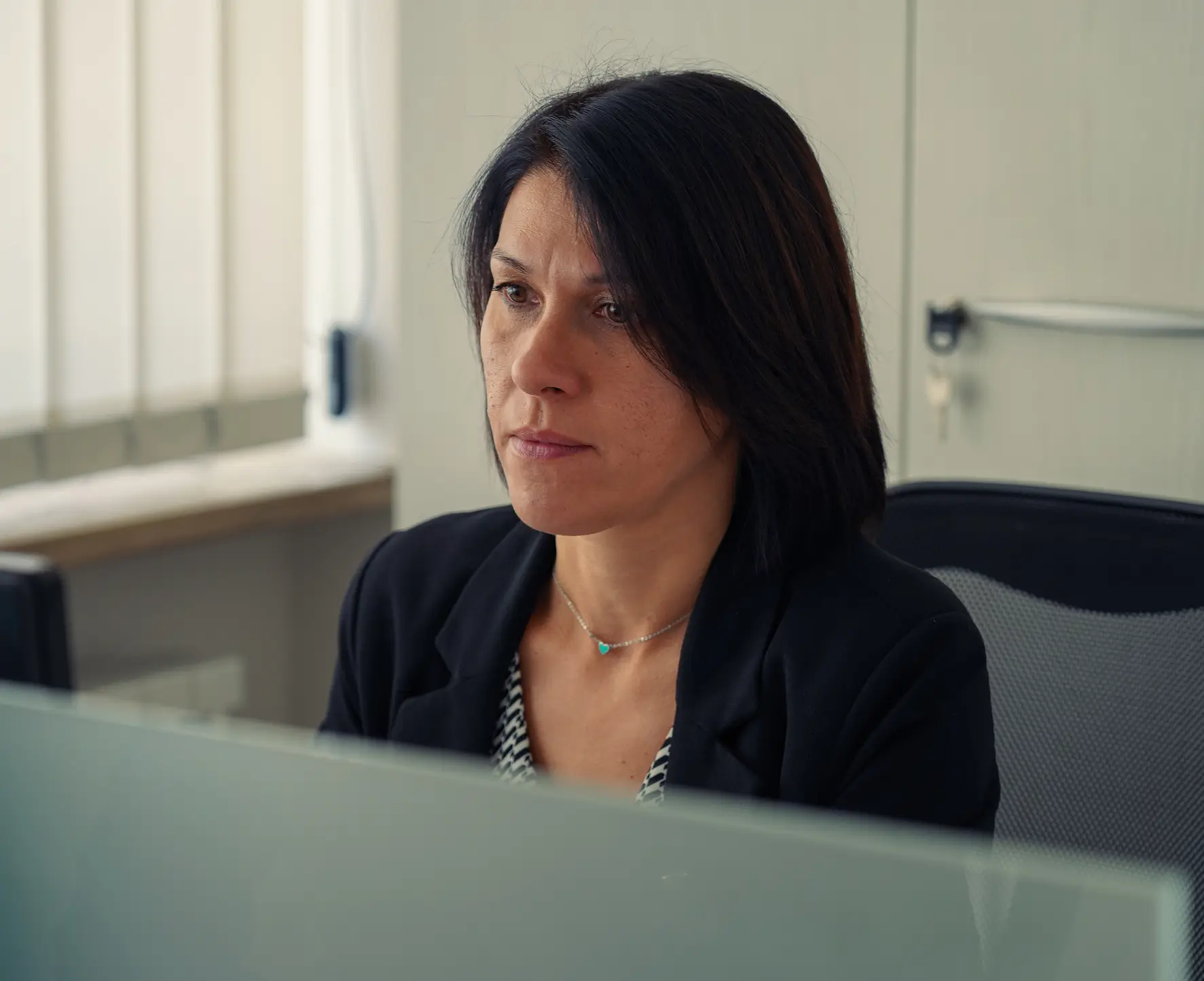 Una donna è seduta a una scrivania e guarda uno schermo.