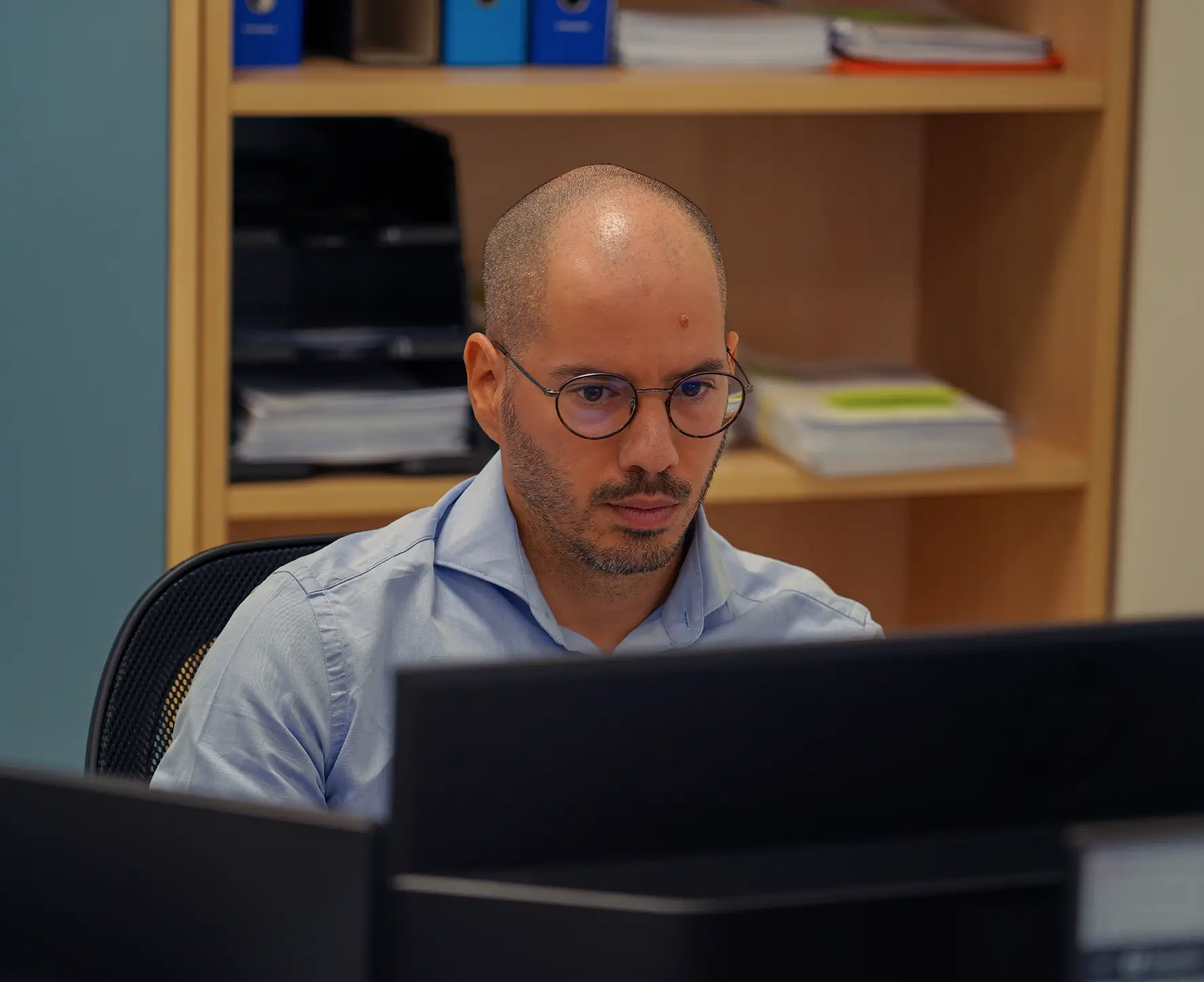 Uomo con gli occhiali che lavora al computer.