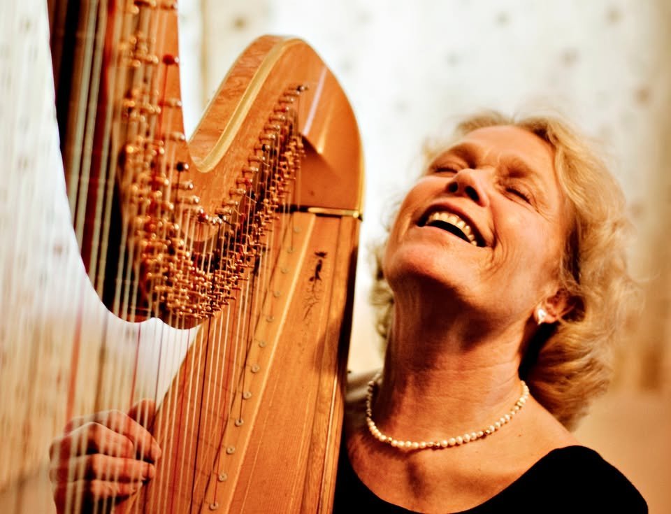 An image of a harp and woman smiling