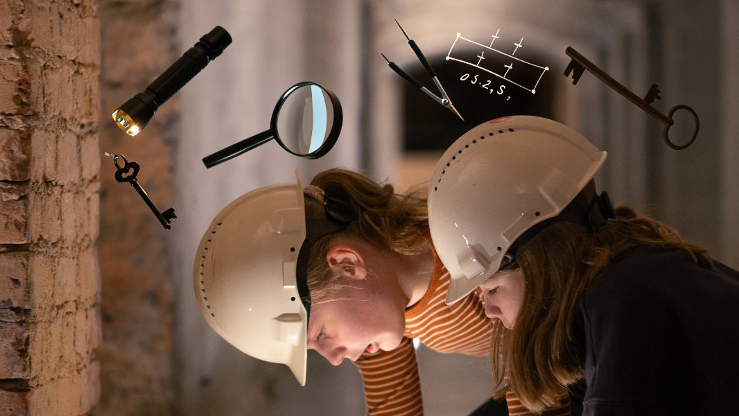 To jenter med hjelm er opptatt med noe de har funnet i en kjeller