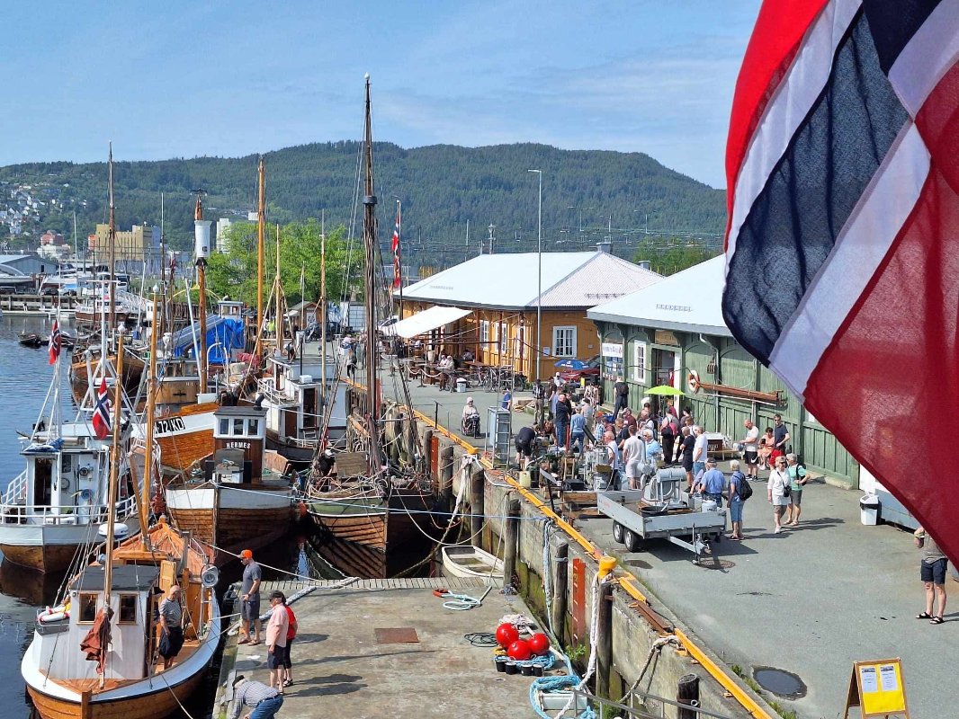 Bilde som viser folk, trebåter og gamle båtmotorer