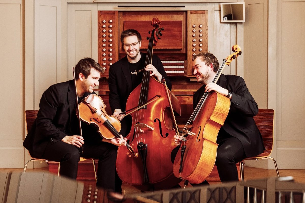 An image of thre men playing accordion string instruments