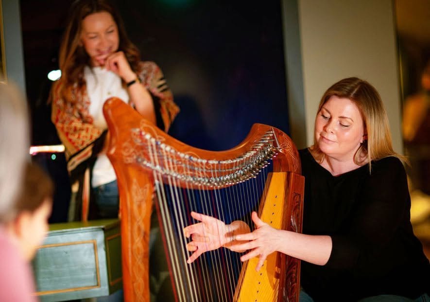 Aan image of a harp and a woman playing
