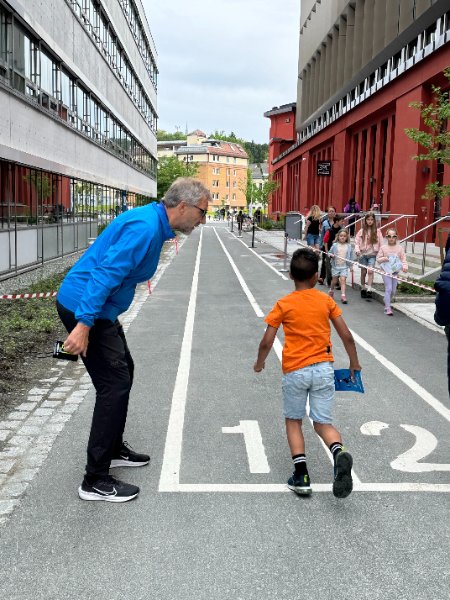 Et barn står klar til å løpe, mens en funksjonær står ved siden av og gir instrukser.