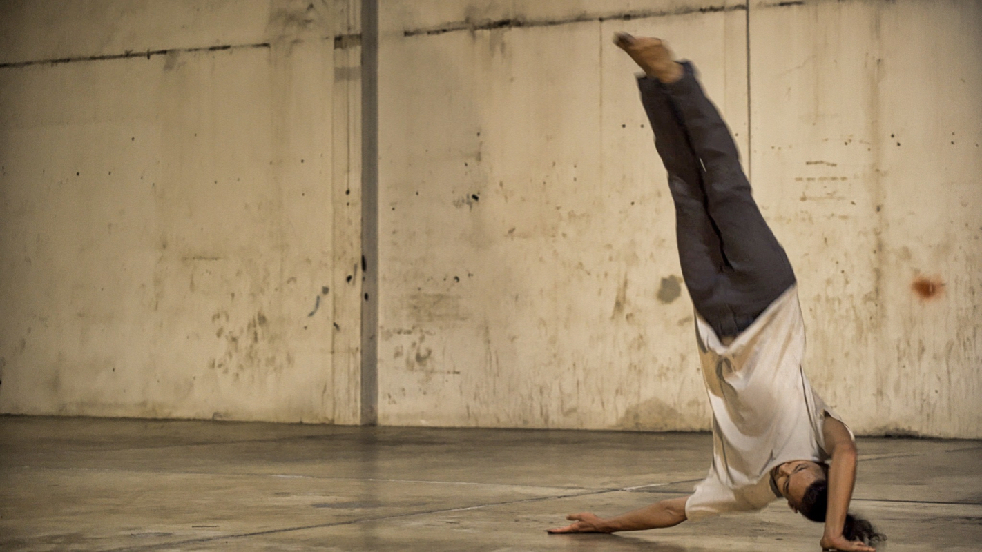 An image of 1 person, practicing dancing upside down with his legs up in the air