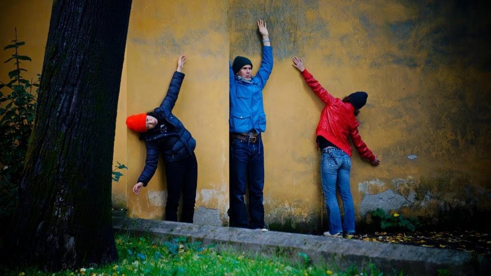 May be an image of three people dancing along a wall