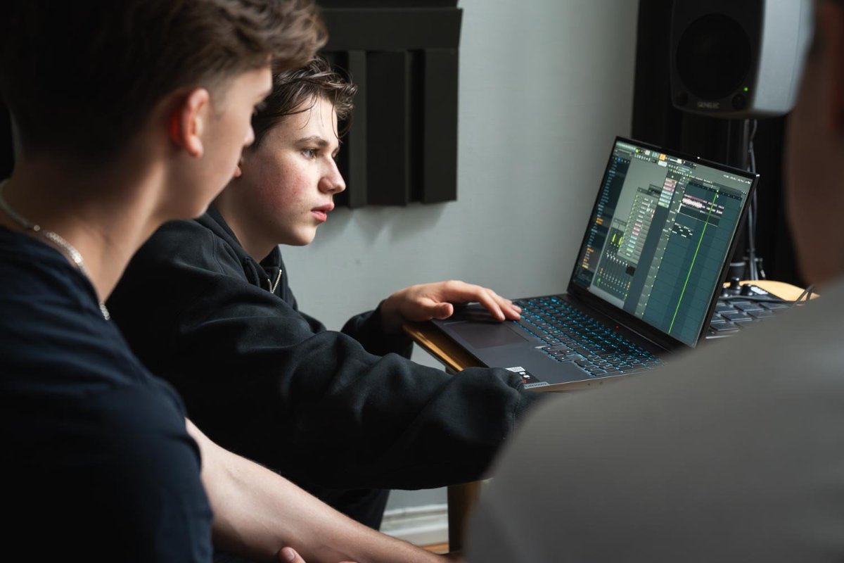 To gutter som studerer dataskjerm i musikkstudio