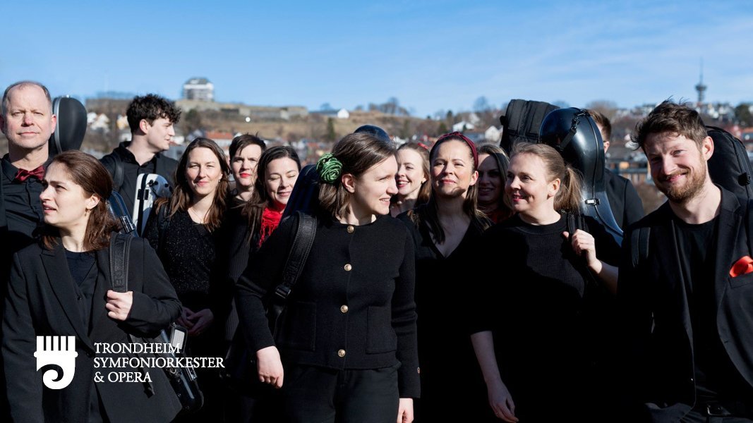 En gruppe musikere som går utendørs i solskinn med instrumentene på ryggen
