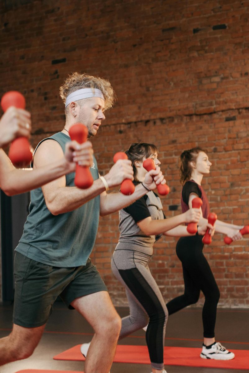 Group exercising with red hand weights in a brick-walled studio