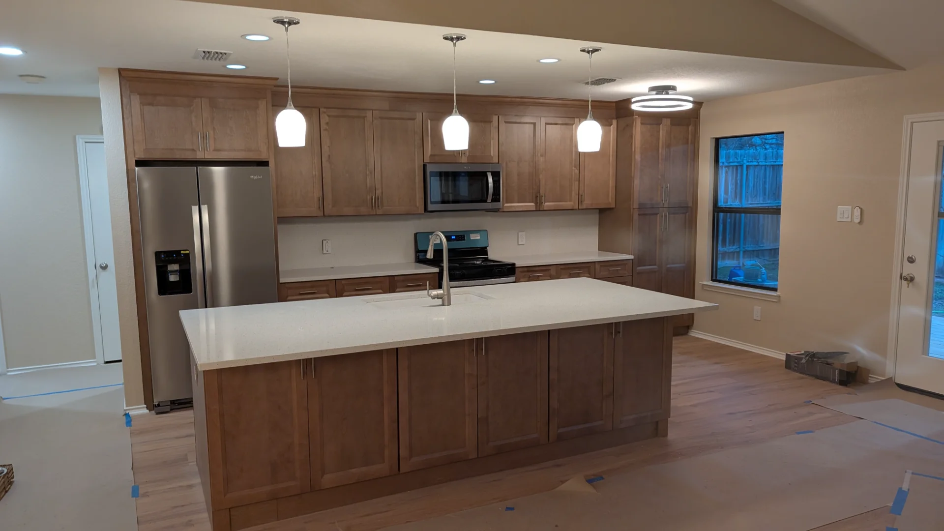 Kitchen remodel in Steiner Ranch, Austin featuring a large white quartz island, dark wood cabinets, and modern pendant lighting, showcasing a high-end aesthetic for homeowners.